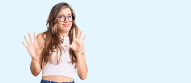 Güzel, beyaz, sıradan kıyafetler ve gözlük takan, korkudan dehşete düşmüş genç bir kadın. El hareketlerini durdur, şok içinde bağır. panik konsepti. 