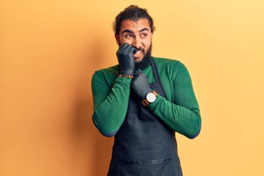 Berber önlüğü takan genç Arap adam gergin ve gergin görünüyor. Ağzı tırnak yiyen ellerle. anksiyete. 