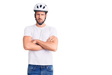 Bisiklet kaskı takan genç yakışıklı, kuşkucu ve gergin. Yüzünde çapraz kollu tasvip etmeyen bir ifade var. negatif kişi. 