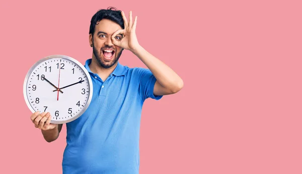 Jovem Hispânico Homem Segurando Grande Relógio Sorrindo Feliz Fazendo Sinal — Fotografia de Stock