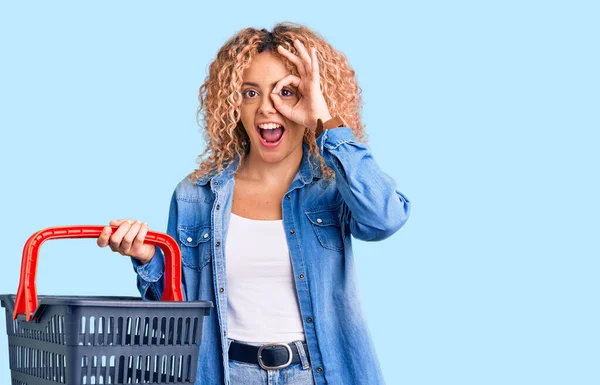 Młoda Blondynka Kręconymi Włosami Trzymając Koszyk Zakupów Supermarket Uśmiechnięty Szczęśliwy — Zdjęcie stockowe