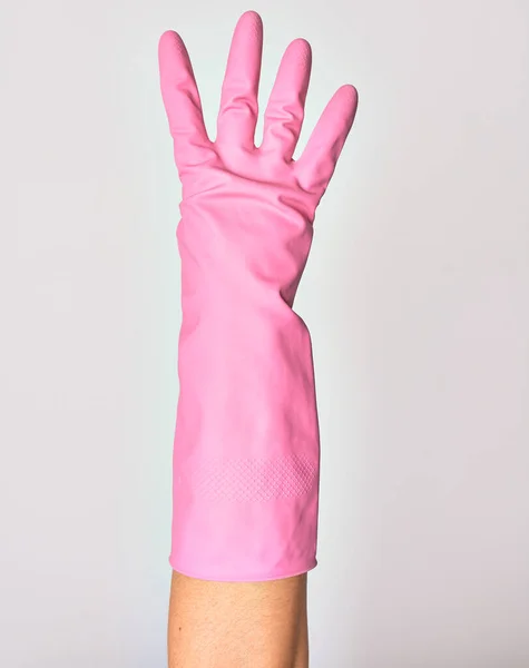 ピンクのクリーニング手袋を身に着けている白人の若い女性の手 孤立した白い背景に4番目の指を示す — ストック写真