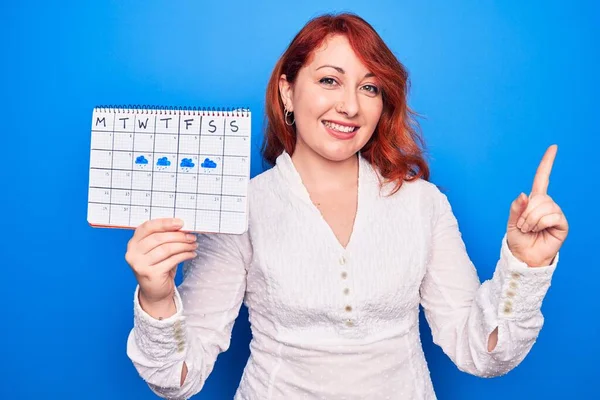 Jonge Roodharige Vrouw Die Weerkalender Toont Regenachtige Week Blauwe Achtergrond — Stockfoto