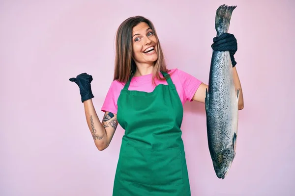 Beautiful Caucasian Woman Fishmonger Selling Fresh Raw Salmon Pointing Thumb — Stock Photo, Image