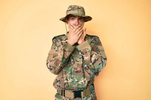 迷彩軍の制服を着た若いハンサムな男がミスのために手で口をカバーショックを受けた 秘密の概念 — ストック写真