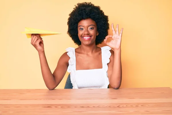 Young African American Woman Holding Paper Airplane Doing Sign Fingers — Stock Photo, Image