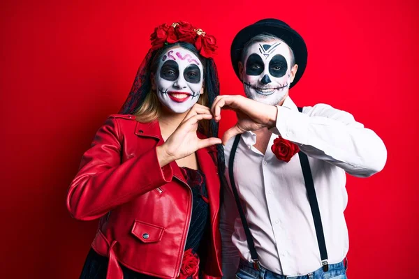 赤い笑顔の上に死んだ衣装の日を身に着けているカップルは手でハートのシンボルの形をして恋に ロマンチックなコンセプト — ストック写真