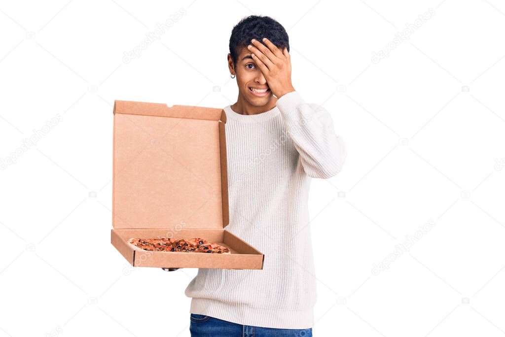 Young african amercian man holding delivery pizza box stressed and frustrated with hand on head, surprised and angry face 