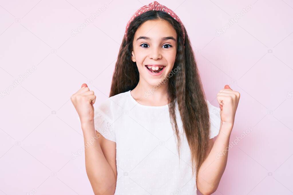 Cute hispanic child girl wearing casual clothes and diadem celebrating surprised and amazed for success with arms raised and open eyes. winner concept. 