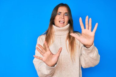 Güzel beyaz kadın kışlık yün süveter giyiyor korku ifadesinden korkuyor ve dehşete düşüyor. El hareketlerini durdur, şok içinde bağır. panik konsepti. 