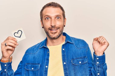 Genç yakışıklı adam elinde kalp ile gururla haykırıyor zaferi ve başarıyı kutluyor. 