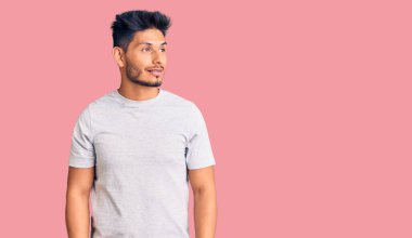 Yakışıklı Latin Amerikalı sıradan tişörtler giyen genç adam yüzünde gülümsemeyle yan yana bakıyor, doğal bir ifade. Kendinden emin gülen. 