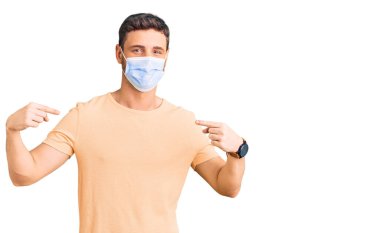 Koronavirüs için tıbbi maske takan yakışıklı genç adam yüzünde gülümsemeyle kendinden emin, gururlu ve mutlu birini işaret ediyor.. 