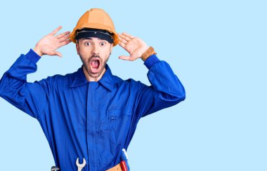 Genç İspanyol işçi üniforması giyen çılgın ve elleri başında korkmuş, korkmuş ve ağzı açık şoktan şaşırmış bir adam. 