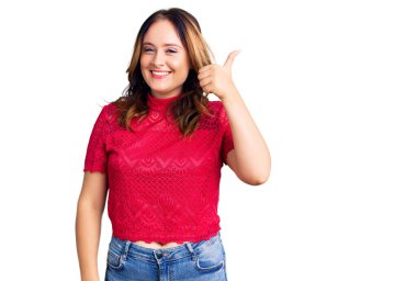 Genç, güzel, beyaz, günlük kıyafetler giyen mutlu ve pozitif gülümseyen, başparmağıyla mükemmel ve onay işareti yapan bir kadın. 