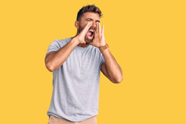 Gündelik kıyafetler giyen genç İspanyol adam elleri ağzında bağırarak bağırıyor. 