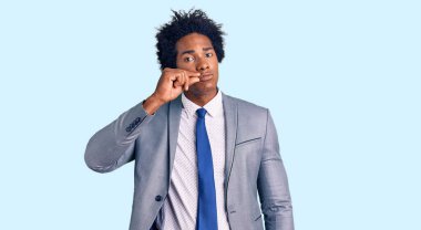 Afro saçlı, iş ceketi giyen, ağzı ve dudakları parmaklarıyla kapanmış yakışıklı Afro-Amerikan erkeği. gizli ve sessiz, tabu konuşması 