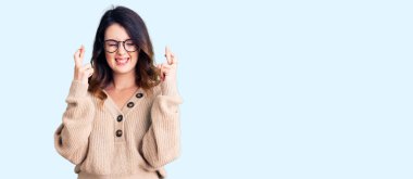 Güzel, genç, esmer bir kadın, günlük kıyafetler ve gözlük takıyor. Umut ve gözlerin kapalı bir şekilde gülümseyerek el sallıyor. Şans ve batıl inançlar. 