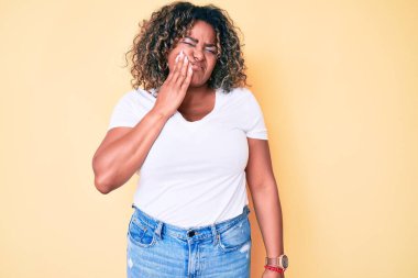 Genç Afro-Amerikan artı iri yarı kadın diş ağrısı ya da diş ağrısı yüzünden ağzıyla dokunan beyaz tişört giyiyor. dişçi 