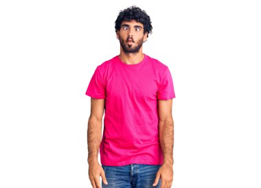 Kıvırcık saçlı yakışıklı genç adam ve günlük pembe tişört giyen ayı dudaklı balık suratı yapan çılgın ve komik bir jest. Komik ifade. 