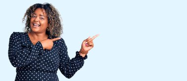 Genç Afro-Amerikan artı cüsseli kadın. Günlük kıyafetler giyiyor. Gülümsüyor ve kameraya bakıyor.. 