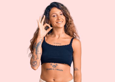 Gündelik kıyafetler giyen, gülümseyen Latin kökenli genç kadın el ve parmaklarıyla 