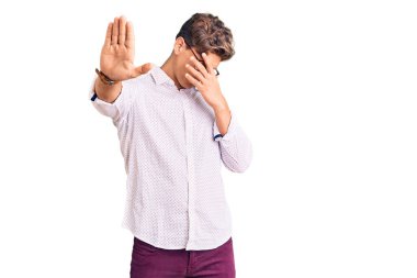 İş kıyafetleri ve gözlük takan genç yakışıklı adam elleriyle gözlerini kapatıyor ve üzgün ve korku ifadeleriyle jest yapıyor. utangaç ve olumsuz kavram. 