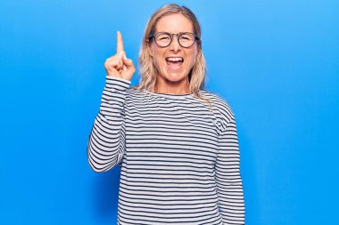 Sıradan çizgili süveter ve gözlük takan orta yaşlı, beyaz bir kadın başarılı bir fikri işaret ediyor. Heyecanlı ve mutlu. Bir numara.. 