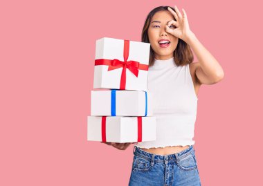 Genç, güzel Çinli kız, elinde hediyeyle gülümsüyor. Mutluluktan gülümsüyor. 