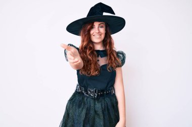 Cadı cadılar bayramı kostümü giymiş genç ve güzel bir kadın selamlaşma ve dostça el sıkışma hediyesi olarak gülümsüyor. başarılı iş. 