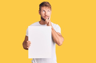 Kafkasyalı genç, boş afiş tutan, ciddi yüzü olan, eli çenesinde soru soran, kafa karıştırıcı bir fikir hakkında düşünceli biri. 