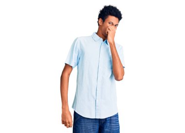 Genç, Afro-Amerikan bir adam günlük giysiler giymiş pis ve iğrenç bir koku alıyor, dayanılmaz bir koku, parmakları burnunda nefesini tutuyor. Kötü kokuyor. 