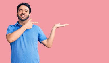 Gündelik kıyafetler giyen genç İspanyol adam kameraya hayret ediyor ve gülümsüyor.. 