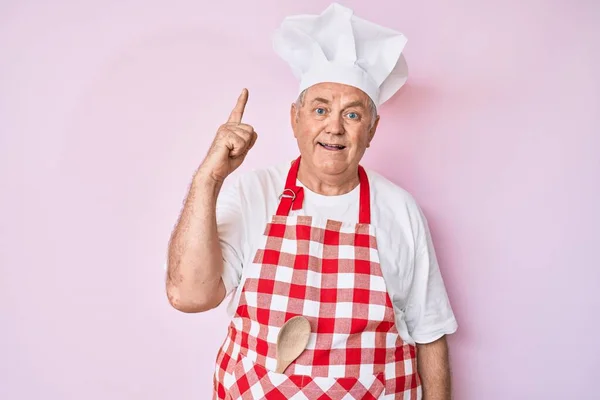 Älterer Grauhaariger Mann Mit Professioneller Bäckerschürze Zeigt Mit Erhobenem Zeigefinger — Stockfoto