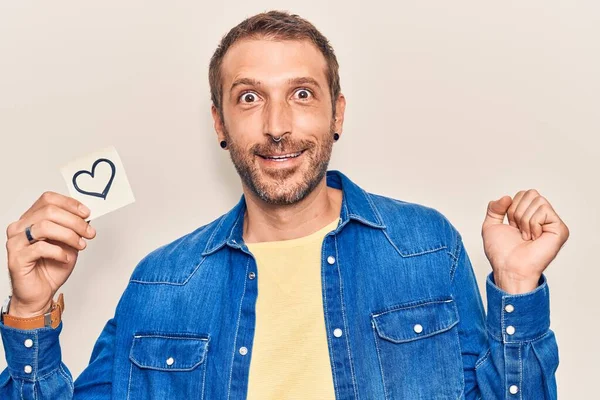 Genç yakışıklı adam elinde kalp ile gururla haykırıyor zaferi ve başarıyı kutluyor. 