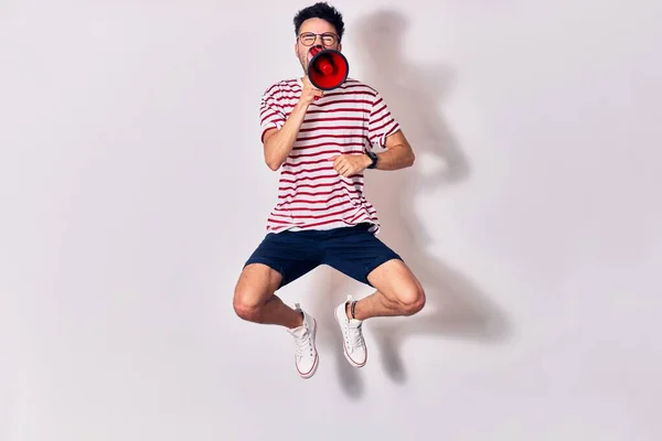 Young Handsome Hispanic Man Wearing Glasses Screaming Using Megaphone Jumping — Stock Photo, Image