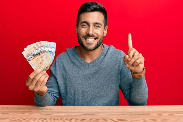 Hombre Hispano Guapo Sosteniendo Dólares Canadienses Sonriendo Con Una Idea — Foto de Stock