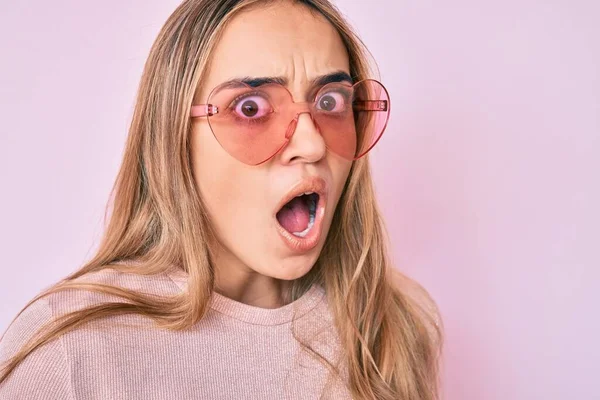 Kalp şeklinde güneş gözlüğü takan genç, güzel sarışın kadın şaşkınlık ve şaşkınlık dolu bir ifade, korku ve heyecan dolu bir yüz ifadesiyle dehşete düşmüş ve şok olmuştu.. 