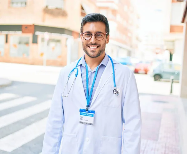 制服を着た若いハンサムなパニック医師と聴診器笑顔幸せ 町の通りで笑顔で立って — ストック写真