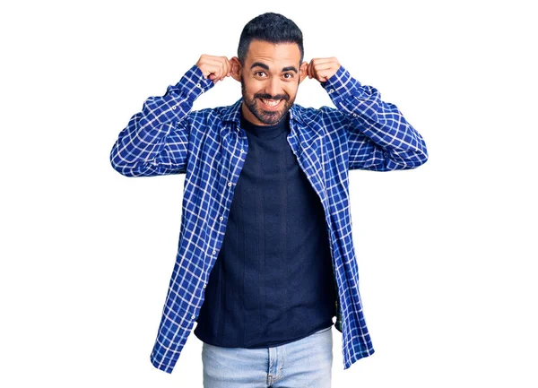 Günlük kıyafetler giyen, gülümseyen, parmaklarıyla kulaklarını çeken genç İspanyol bir adam, komik bir jest. deneme sorunu 