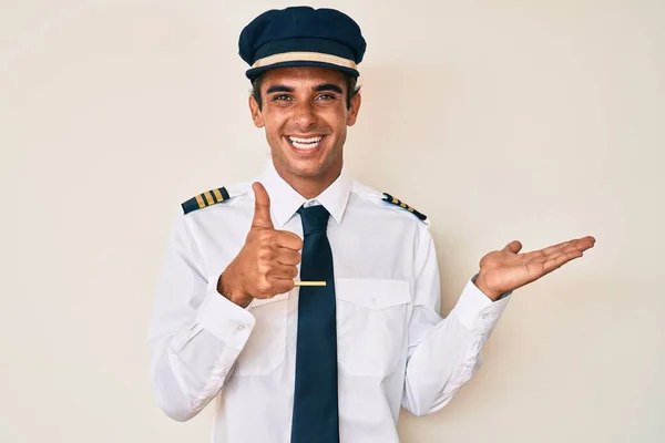 Junger Hispanischer Mann Flugzeugpilotenuniform Zeigt Handfläche Und Macht Geste Mit — Stockfoto