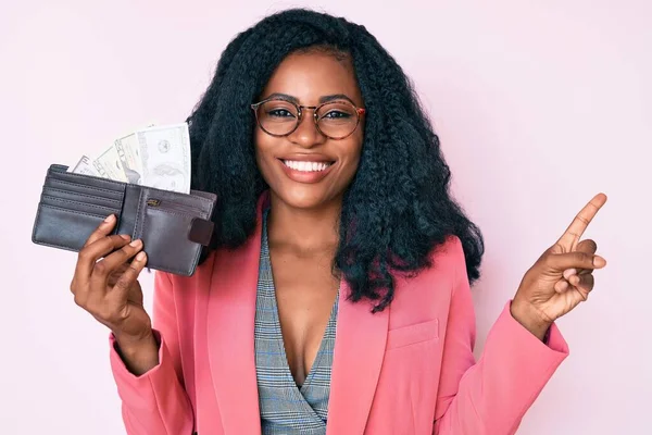 Hermosa Mujer Africana Sosteniendo Cartera Con Dólares Sonriendo Feliz Señalando —  Fotos de Stock