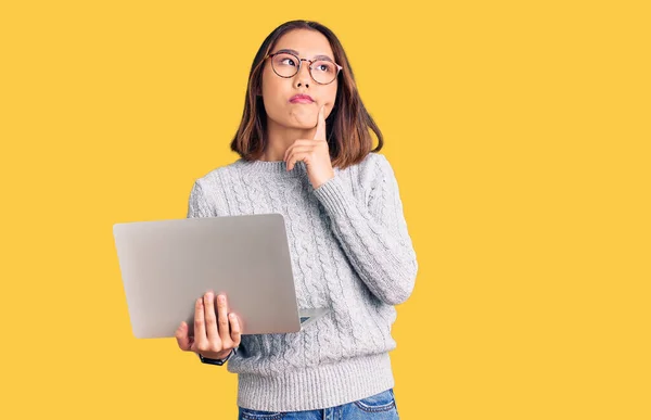 Молода Красива Китайка Окулярах Тримає Ноутбук Серйозне Обличчя Думаючи Про — стокове фото