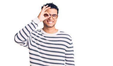 İspanyol yakışıklı genç adam günlük kıyafetler ve gözlük takıyor. El hareketleriyle gülümsüyor, gözleriyle mutlu yüzle parmaklarının arasından bakıyor.. 