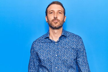 Yüzünde ciddi bir ifade olan sıradan kıyafetler giyen genç yakışıklı bir adam. Basit ve doğal bir şekilde kameraya bakıyorsun.. 