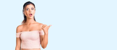 Gündelik kıyafetler giyen genç ve güzel bir kadın elleri yana doğru işaret ederek şaşırdı, ağzı açık hayret içinde kaldı.. 