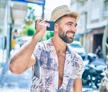 Genç İspanyol adam tatilde gülümsüyor. Şehrin caddesinde akıllı telefon kullanıyor.