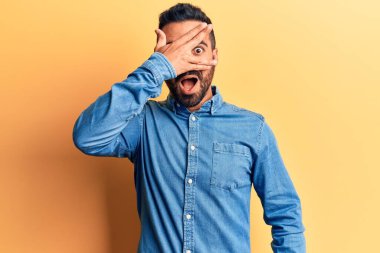 Gündelik kıyafetler giyen genç İspanyol adam şok içinde yüzünü ve gözlerini kapayarak utanmış ifadesiyle parmaklarından bakıyor.. 