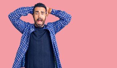 Gündelik kıyafetler giyen genç İspanyol adam çılgın ve elleri başında korkmuş, ağzı açık şoktan korkmuş ve şaşırmış. 