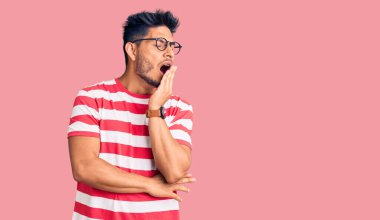 Yakışıklı Latin Amerikalı sıradan kıyafetler ve gözlük takan genç adam ağzıyla esnemekten sıkılmış. Huzursuz ve uykulu.. 